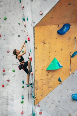 Tırmanma merkezinde taş duvarda pratik yapan tatlı bir genç kız. Sportif yaşam tarzı, aktivite, mutlu çocukluk kavramı