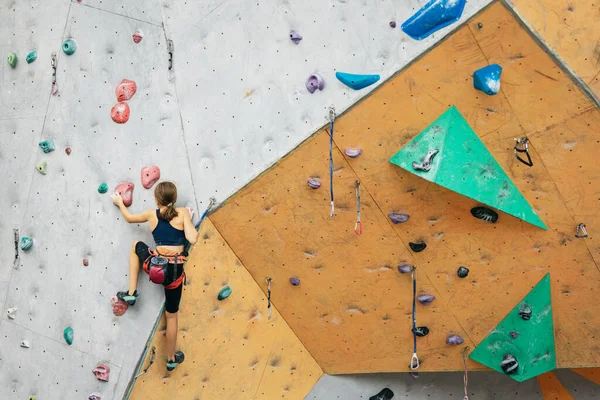 Uma menina adolescente bonito praticando na parede de rocha no centro de escalada. Conceito de estilo de vida esportivo, atividade, infância feliz — Fotografia de Stock