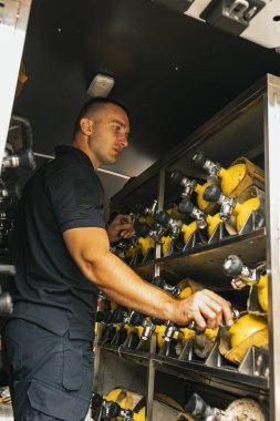 Erkek itfaiyeci kamyonda yangın söndürücü tutuyor.