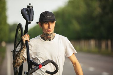 Bisikletli genç bir erkek. Yaz akşamları yolda yürüyor.