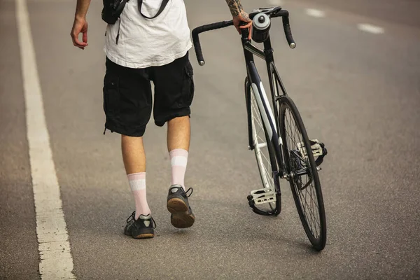 Young male cyclist with a bike on road