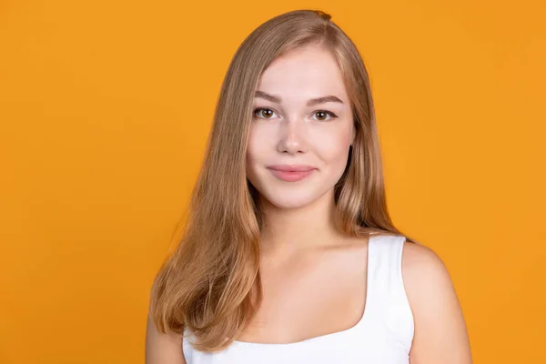 Cute uśmiechnięta młoda kobieta portret izolowany na pomarańczowym tle studio — Zdjęcie stockowe