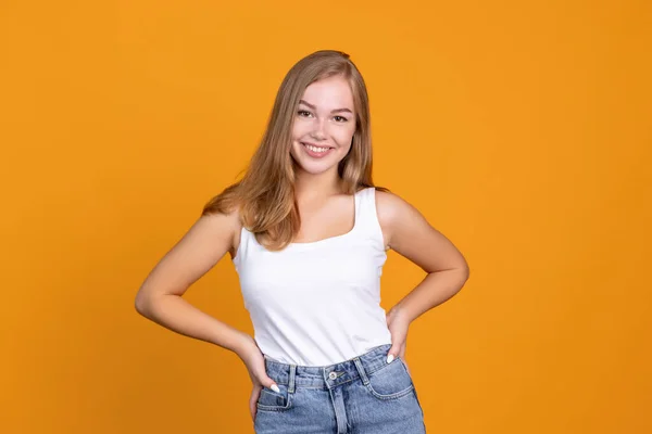Halblanges Porträt der jungen schönen lächelnden Mädchen isoliert auf orangefarbenem Studiohintergrund — Stockfoto