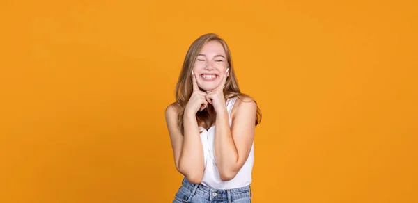 Lächelt weiter. Fröhliches junges Mädchen lächelt auf orangefarbenem Backblech — Stockfoto