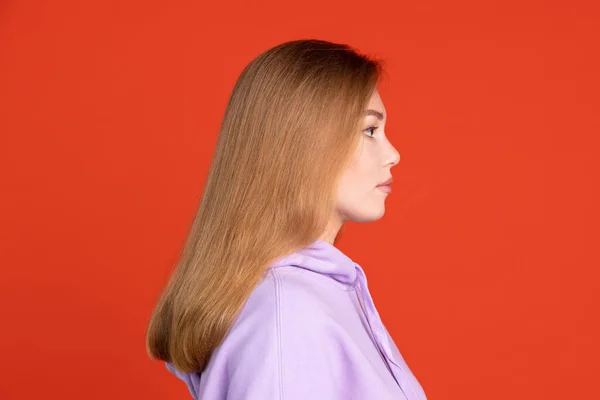 Pół długości boczny portret widok beautigul młodej dziewczyny izolowane na czerwonym tle studio. Pojęcie ludzkich emocji — Zdjęcie stockowe