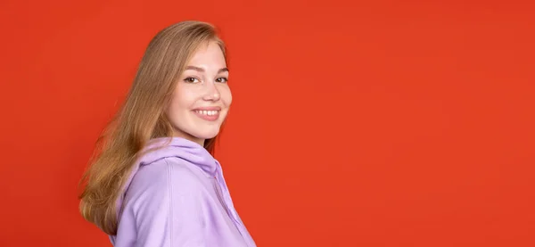 Vista laterale ritratto ritagliato di giovane ragazza sorridente isolato su sfondo rosso studio. Concetto di emozioni umane — Foto Stock