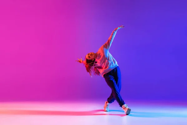 Jong mooi meisje, vrouwelijke hip-hop danser geïsoleerd op gradiënt roze paars neon studio achtergrond — Stockfoto