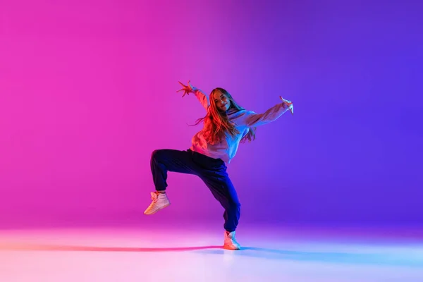 Attraente ragazza che balla hip-hop isolato sul gradiente rosa viola neon studio sfondo — Foto Stock