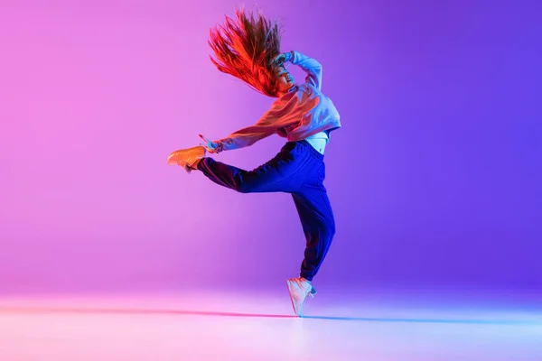 Joven chica elegante bailando hip-hop aislado en degradado rosa púrpura estudio de neón fondo — Foto de Stock