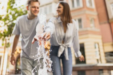 Genç bir çiftin ılık bir yaz günü çeşmenin yanında eğlenirken çekilmiş bulanık bir fotoğrafı.