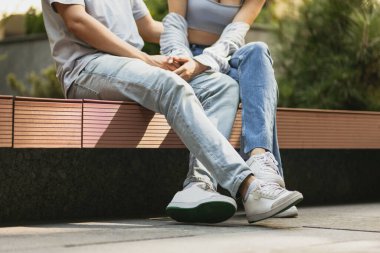 Bankta oturan iki kişinin bacak görüntüsü.