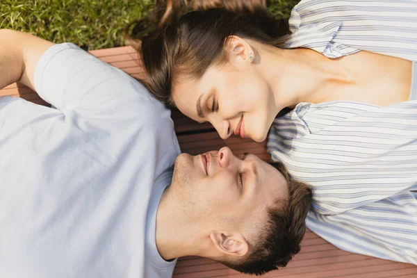 Gros plan portrait recadré de jeune beau couple couché sur le banc en pose de yin yang — Photo