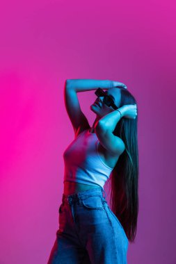 Genç ve güzel bir kız pembe mor arka planda izole edilmiş.