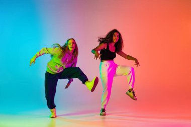 Rengarenk arka planda iki güzel hip-hop dansçısı neon ışıklarıyla