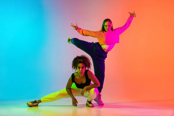 Due belle ragazze che ballano hip-hop su sfondo sfumato colorato in luci al neon — Foto Stock