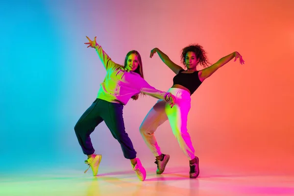 Ausdruck. Zwei schöne stylische Hip-Hop-Tänzer auf farbenfrohem Gradienten-Hintergrund im Neonlicht — Stockfoto