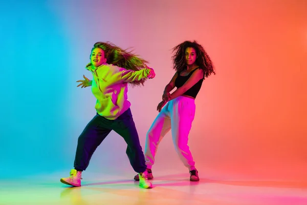 Dos hermosas bailarinas de hip-hop con estilo sobre fondo degradado colorido en luces de neón — Foto de Stock