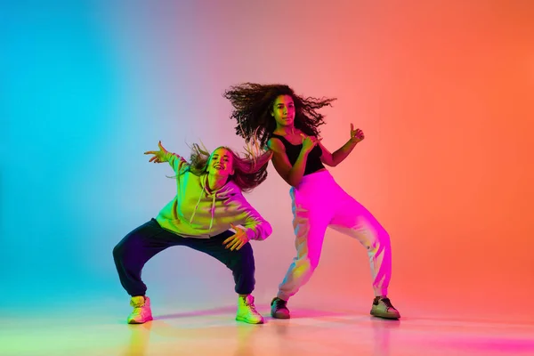 Two beautiful stylish hip-hop dancers on colorful gradient background in neon lights — Stock Photo, Image