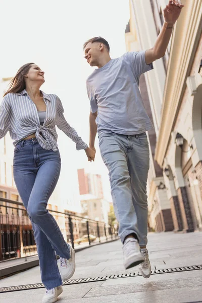 Повнометражний портрет молодої щасливої пари в русі. Прогулянки містом в теплий сонячний день — стокове фото