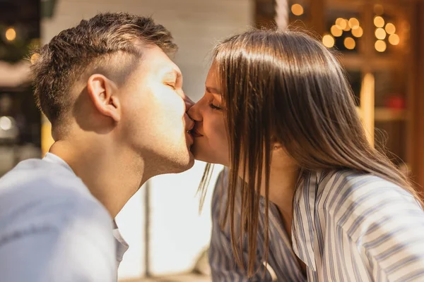 Genç ve güzel bir çiftin parlak bir yaz gününde kafede oturup öpüşürken çekilmiş portresi. — Stok fotoğraf