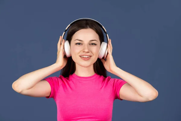 Portrait de jeune souriante belle fille caucasienne avec écouteurs isolés sur fond bleu — Photo