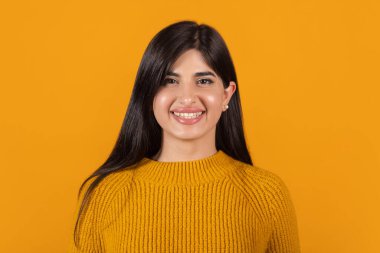 Turuncu stüdyo arka planında izole edilmiş güzel bir kızın yakın planda çekilmiş portresi.