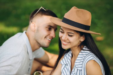 Neşeli konuşma. Genç güzel arkadaşlar çimenlerde oturup, piknik yapıp, sohbet ediyorlar.