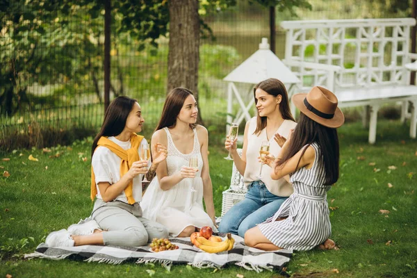 Vier mooie jonge meisjes zitten op gras en picknick — Stockfoto