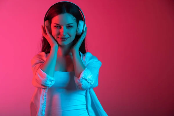 Portrait recadré de jeune belle fille avec écouteurs sur dégradé rose rouge fond studio — Photo