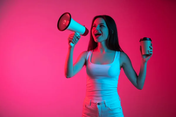 Przycięty obraz ekspresyjnej młodej dziewczyny z megafonem na gradientowym różowym czerwonym tle w neonach — Zdjęcie stockowe