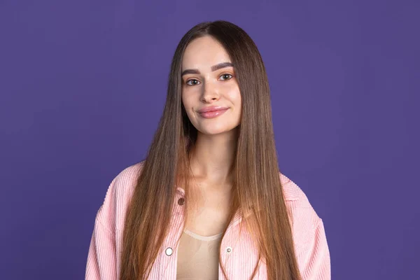 Közelkép portré fiatal aranyos lány alig mosolyog a kamera lila stúdió háttér — Stock Fotó