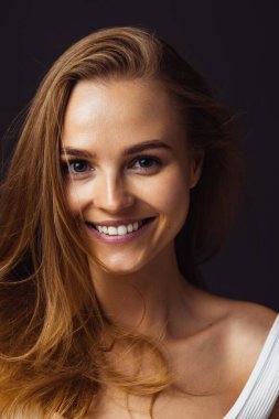 Koyu kahverengi stüdyo arka planında izole edilmiş güzel, gülümseyen beyaz kadın portresi.