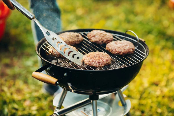 Close-up photo of burger cutlets on grill. Tasty food cooking. Friends picnic on warm summer day — Stock Photo, Image