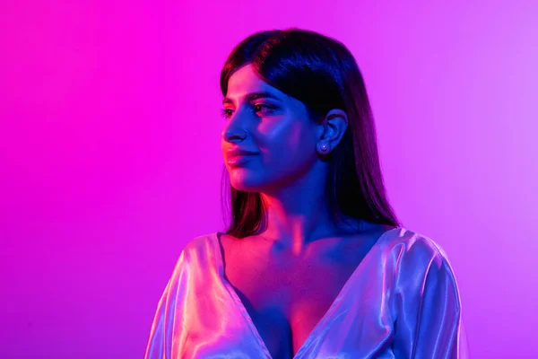 Neon ışıklarıyla gradyan stüdyo arka planında poz veren güzel kadın modelin kırpılmış portresi. — Stok fotoğraf