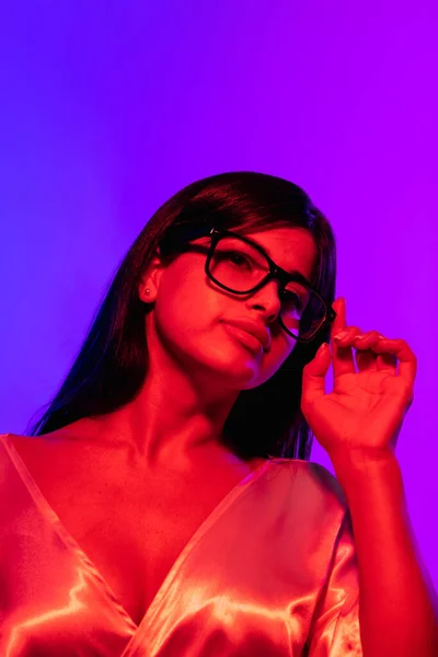 Gesneden portret van jong mooi meisje dragen bril geïsoleerd over gradiënt achtergrond in neon — Stockfoto