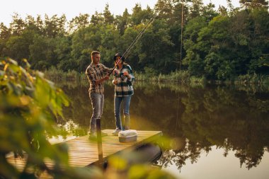 Sıcak yaz gününde gün batımında kırsalda balık tutan genç bir çiftin portresi.