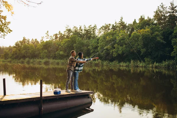 Retrato de larga duración de una pareja joven pescando en el cálido día de verano en el campo temprano en la mañana —  Fotos de Stock