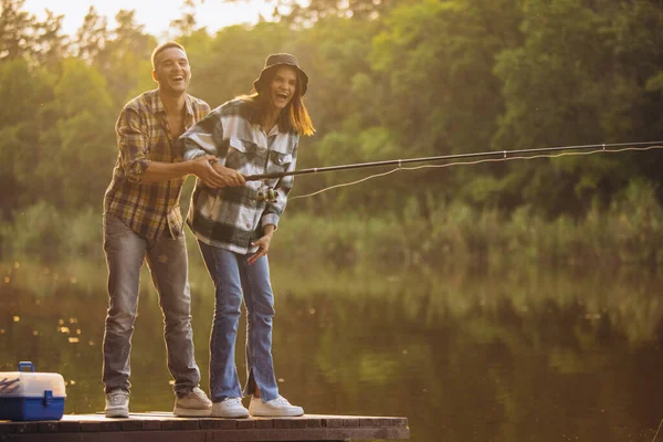 Ritratto di giovane coppia che pesca nella calda giornata estiva in campagna al tramonto — Foto Stock