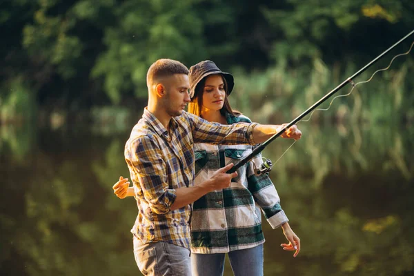 Retrato horizontal de dos jóvenes, hombre y mujer, pescando juntos en el cálido día de verano en el campo al atardecer —  Fotos de Stock