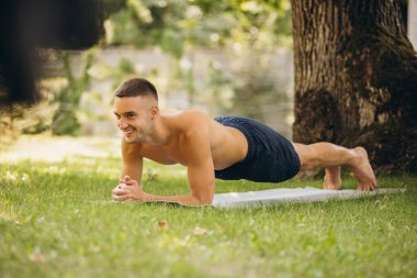 Sıcak bir yaz gününde dışarıda yoga yapan yakışıklı bir adamın tam boy portresi.