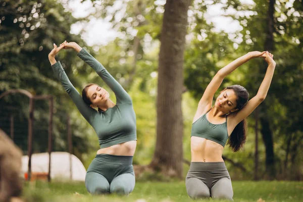 Due belle giovani donne che fanno yoga e stretching esercizi all'aperto nella calda giornata estiva — Foto Stock