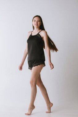 Pembe stüdyo arka planında ipek pijamalı beyaz bir kadın.