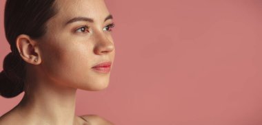 Pembe stüdyo arka planında izole edilmiş güzel bir kızın kesilmiş portresi.