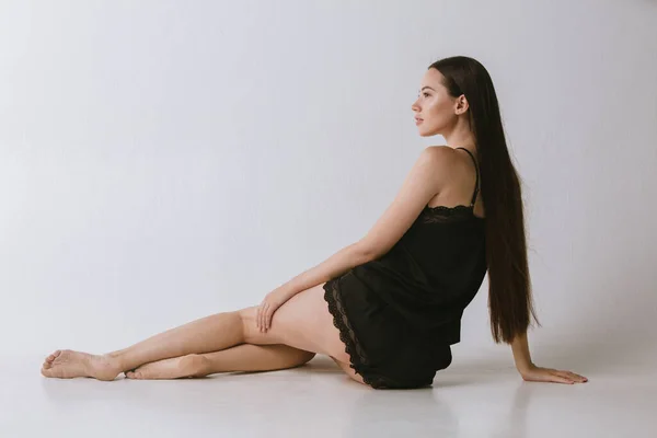 Portrait horizontal recadré de jeune modèle féminin en usure intérieure posant sur fond de studio gris — Photo