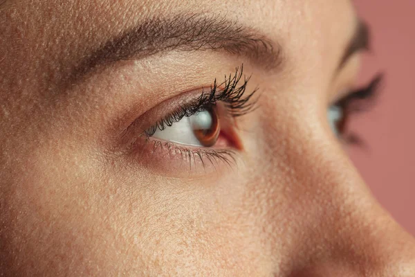 Imagen de cerca de hermosos ojos femeninos marrones. Mujer aislada sobre fondo rosa — Foto de Stock
