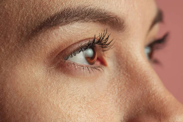 Close-up image of beautiful brown female eyes. Woman isolated over pink background — Stock Photo, Image