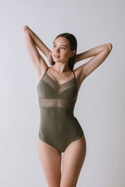 Gri arka planda izole edilmiş yeşil iç giysili genç ve güzel kızın kesilmiş portresi.