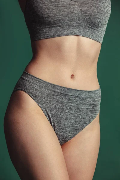 Närbild passform kvinnlig kropp i grå bomull underkläder över grön bakgrund. — Stockfoto