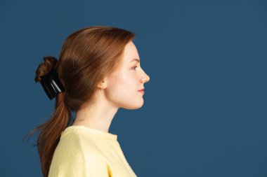 Koyu mavi arka planda izole edilmiş at kuyruklu beyaz kadın portresi.