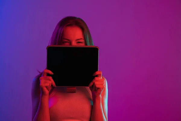 네온등의 일정 한 배경 위에 태블릿 장치를 설치 한 예쁜 소녀의 모습. 온라인 교육 — 스톡 사진
